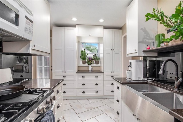 1307 W 30th St S, Independence, MO 64052 - kitchen featuring white microwave, a sink, stainless steel range with gas cooktop, white cabinetry, and recessed lighting