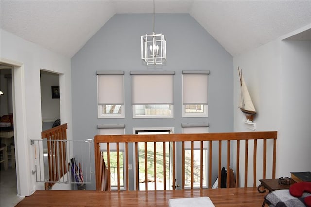 7833 Garnett St, Lenexa, KS 66214 - hallway featuring a chandelier, wood finished floors, healthy amount of natural light, high vaulted ceiling, and an upstairs landing