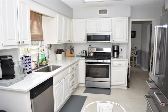 7833 Garnett St, Lenexa, KS 66214 - kitchen with appliances with stainless steel finishes, a sink, white cabinets, light countertops, and light tile patterned floors