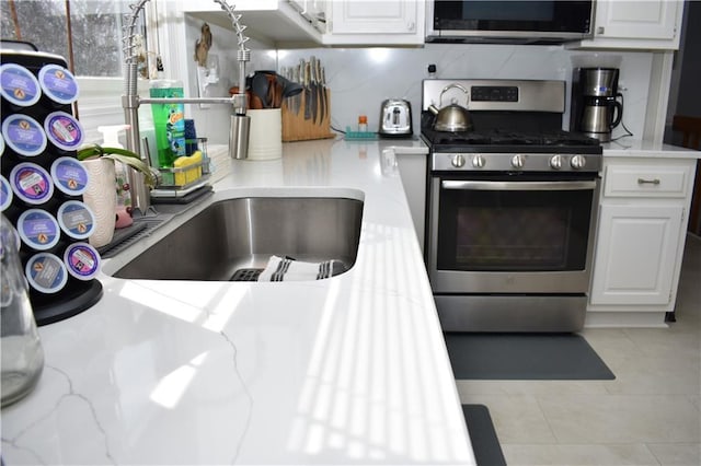 7833 Garnett St, Lenexa, KS 66214 - kitchen featuring stainless steel appliances, white cabinets, light tile patterned floors, and a sink