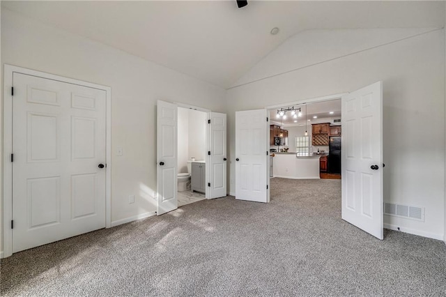 812 E 110th Ter, Kansas City, MO 64131 - unfurnished bedroom with freestanding refrigerator, vaulted ceiling, carpet, and connected bathroom