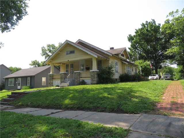 201 E Ottawa St, Paola, KS 66071 - view of front of home with covered porch, a front lawn, and stone siding