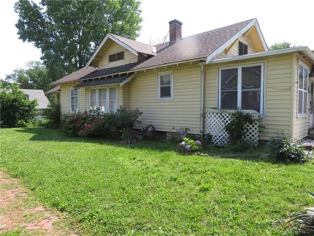 201 E Ottawa St, Paola, KS 66071 - rear view of house featuring a chimney, a lawn, and roof with shingles