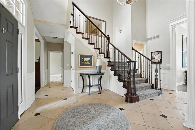 9905 W 144th St, Overland Park, KS 66221 - foyer entrance with stairs, a high ceiling, light tile patterned floors, a decorative wall, and wainscoting