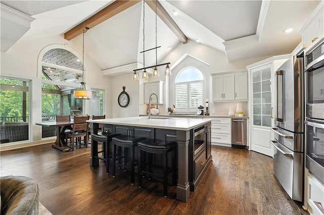 9905 W 144th St, Overland Park, KS 66221 - kitchen featuring a breakfast bar area, light countertops, dark wood finished floors, a center island with sink, and hanging light fixtures