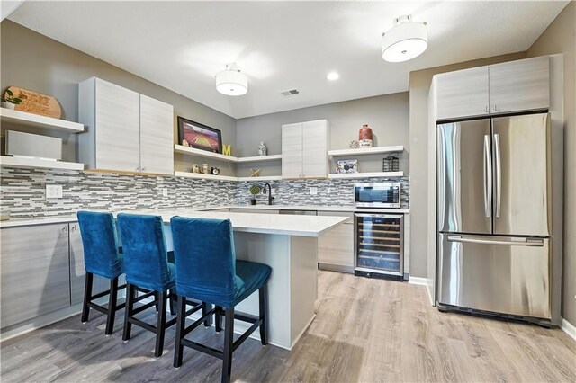 9905 W 144th St, Overland Park, KS 66221 - kitchen featuring open shelves, stainless steel appliances, wine cooler, a breakfast bar area, and recessed lighting