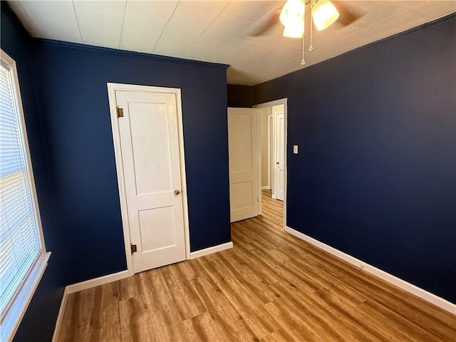 612 W Walnut St, Independence, KS 67301 - unfurnished bedroom with wood finished floors, baseboards, multiple windows, and ceiling fan
