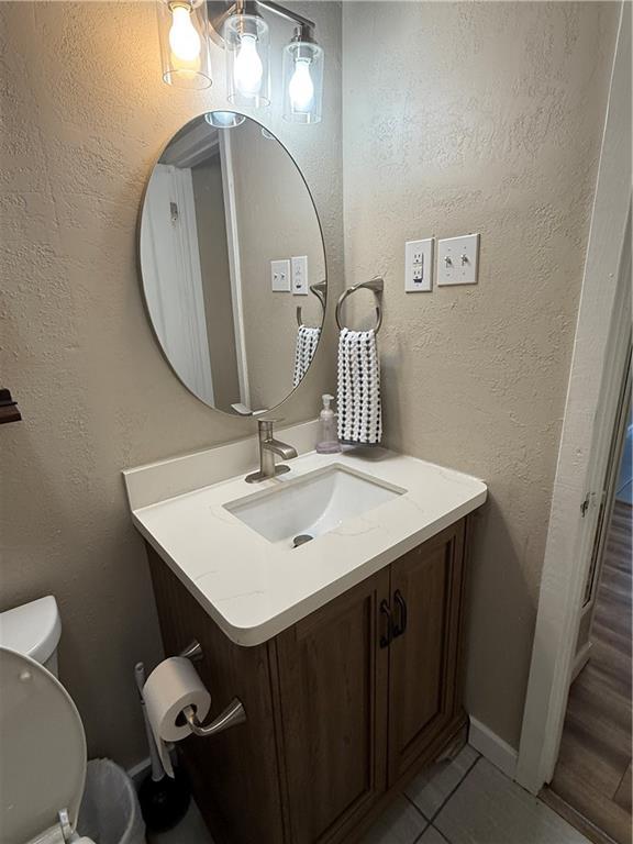 612 W Walnut St, Independence, KS 67301 - half bathroom featuring vanity, toilet, tile patterned flooring, and baseboards