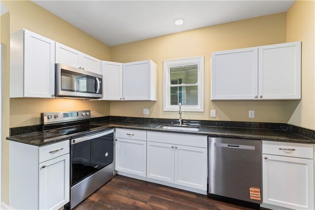 2717 Bales Ave, Kansas City, MO 64128 - kitchen with stainless steel appliances, white cabinets, dark wood-style floors, and dark stone counters