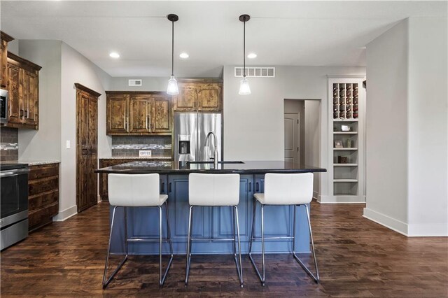 4529 Lakecrest Dr, Shawnee, KS 66218 - kitchen featuring stainless steel appliances, dark wood-style flooring, decorative backsplash, a breakfast bar area, and recessed lighting