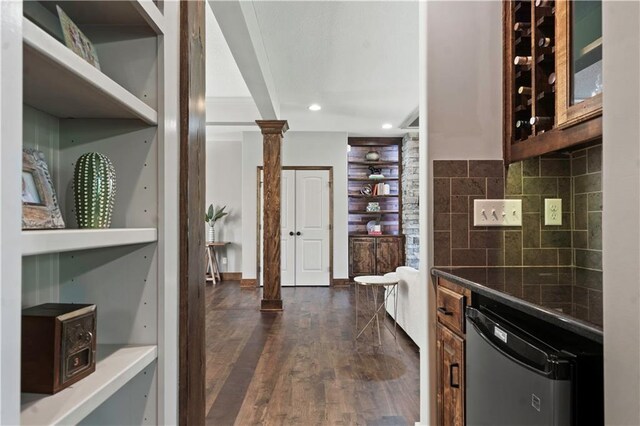 4529 Lakecrest Dr, Shawnee, KS 66218 - kitchen with stainless steel dishwasher, decorative columns, dark wood-type flooring, decorative backsplash, and glass insert cabinets