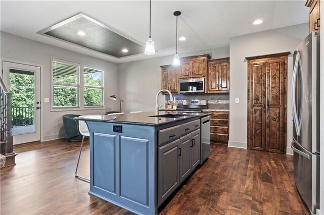 4529 Lakecrest Dr, Shawnee, KS 66218 - kitchen featuring appliances with stainless steel finishes, dark countertops, tasteful backsplash, dark wood-style floors, and an island with sink