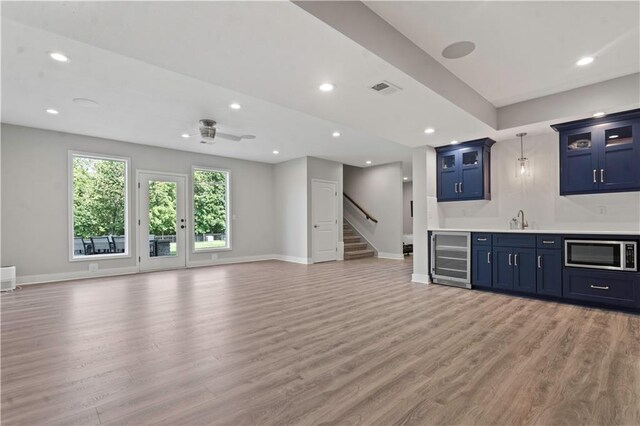 4529 Lakecrest Dr, Shawnee, KS 66218 - indoor wet bar with stainless steel microwave, beverage cooler, light wood-style flooring, recessed lighting, and stairs