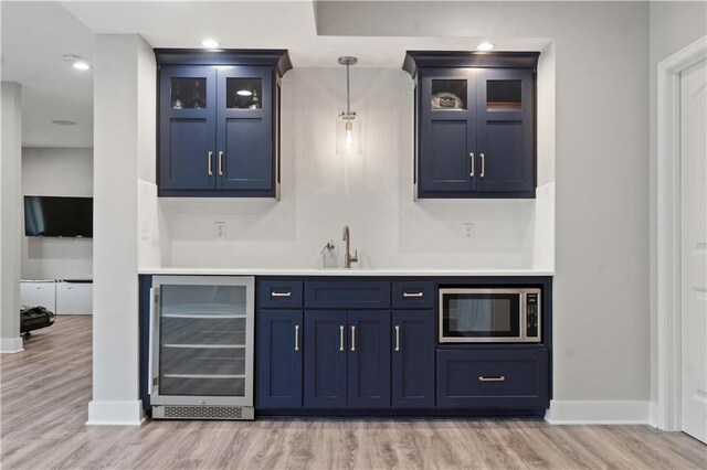 4529 Lakecrest Dr, Shawnee, KS 66218 - indoor wet bar with stainless steel microwave, wine cooler, light wood-type flooring, decorative light fixtures, and decorative backsplash