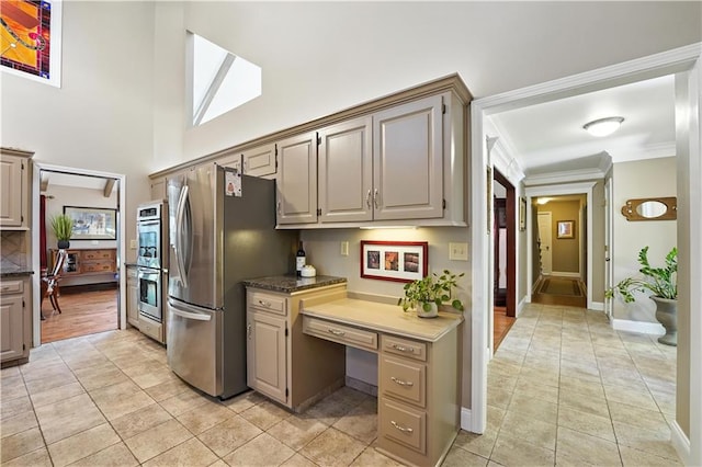 12032 Ballentine St, Overland Park, KS 66213 - kitchen featuring stainless steel appliances, light tile patterned floors, a high ceiling, ornamental molding, and built in study area