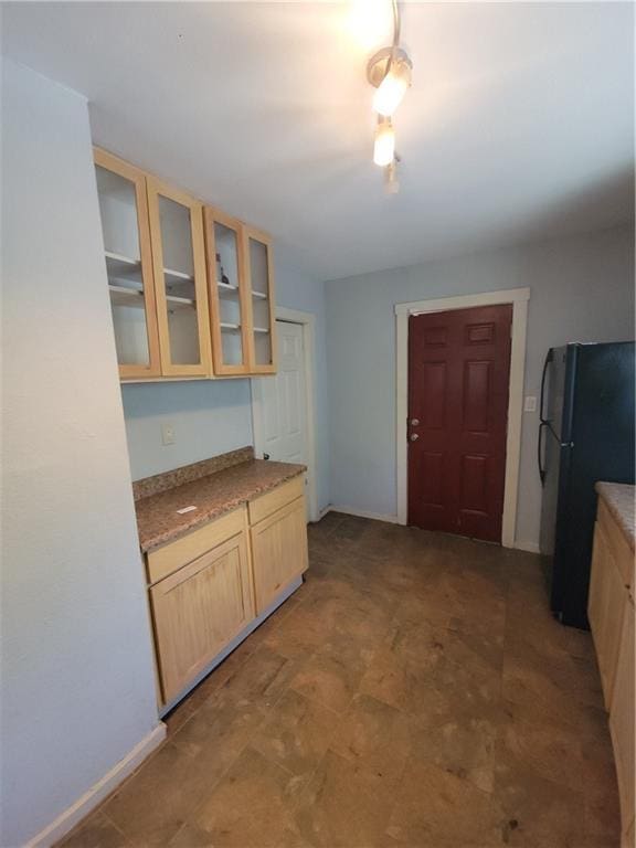 5000 Agnes Ave, Kansas City, MO 64130 - kitchen featuring freestanding refrigerator, light brown cabinets, and glass insert cabinets