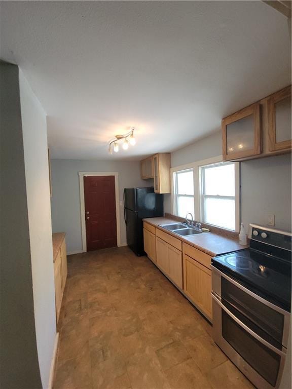 5000 Agnes Ave, Kansas City, MO 64130 - kitchen featuring double oven range, freestanding refrigerator, light countertops, light brown cabinetry, and glass insert cabinets