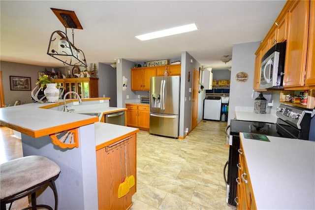 22920 Feaster Branch Rd, Warsaw, MO 64355 - kitchen with appliances with stainless steel finishes, a sink, washer / clothes dryer, light countertops, and a breakfast bar area