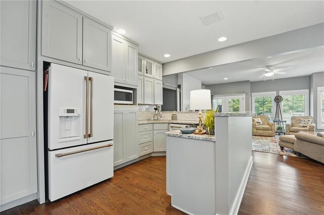 9 P St, Lees Summit, MO 64086 - kitchen with white appliances, a peninsula, open floor plan, tasteful backsplash, and dark wood-style floors