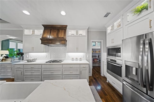 16600 Eby St, Overland Park, KS 66085 - kitchen with appliances with stainless steel finishes, ornamental molding, tasteful backsplash, white cabinetry, and custom exhaust hood