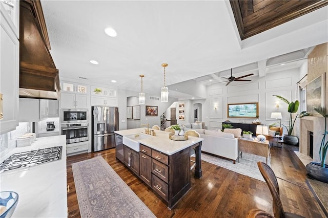 16600 Eby St, Overland Park, KS 66085 - kitchen with appliances with stainless steel finishes, dark brown cabinetry, light countertops, a fireplace, and dark wood finished floors