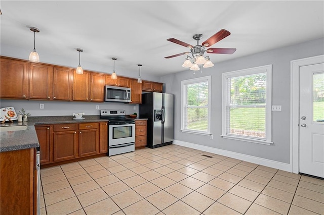 5016 Lydia Ave, Kansas City, MO 64110 - kitchen with stainless steel appliances, dark countertops, brown cabinets, a ceiling fan, and decorative light fixtures