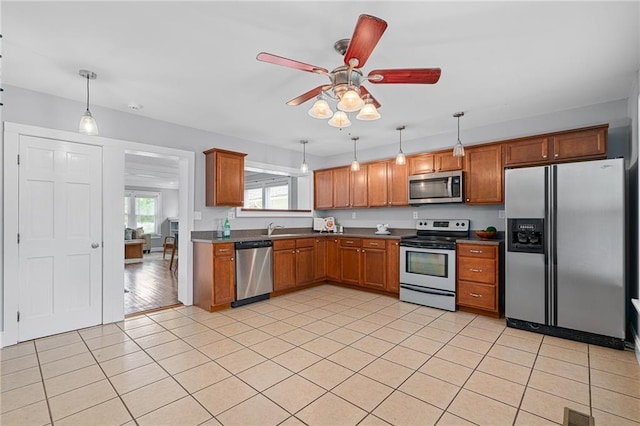 5016 Lydia Ave, Kansas City, MO 64110 - kitchen featuring appliances with stainless steel finishes, ceiling fan, light tile patterned floors, brown cabinetry, and hanging light fixtures