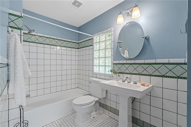5016 Lydia Ave, Kansas City, MO 64110 - full bath with tile walls, shower / washtub combination, tile patterned floors, and a wainscoted wall