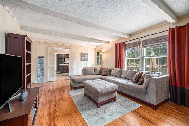 9412 Delmar St, Prairie Village, KS 66207 - living room with beamed ceiling, a textured ceiling, light wood-style flooring, and wood walls