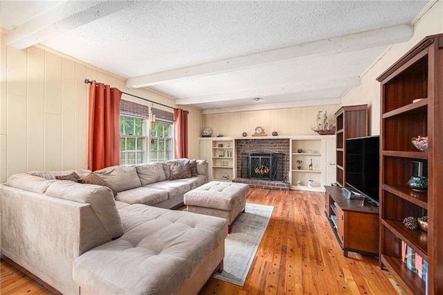 9412 Delmar St, Prairie Village, KS 66207 - living room with beam ceiling, light wood-style floors, a textured ceiling, a fireplace, and wood walls