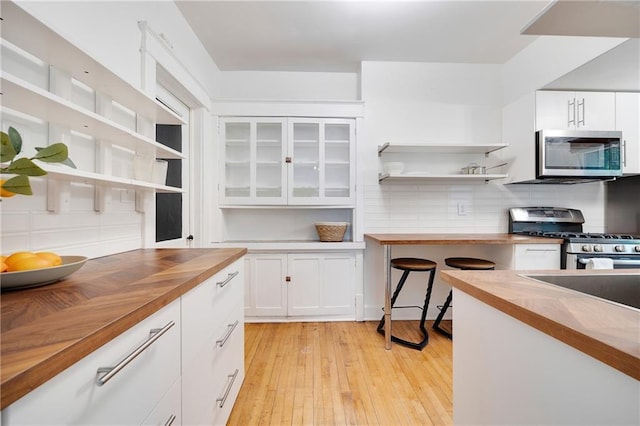 3029 E 7th St, Kansas City, MO 64124 - kitchen with wood counters, stainless steel appliances, open shelves, and white cabinets