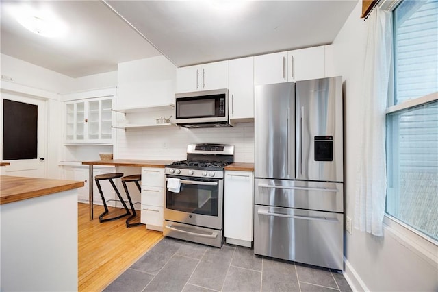 3029 E 7th St, Kansas City, MO 64124 - kitchen featuring appliances with stainless steel finishes, butcher block counters, white cabinetry, and backsplash