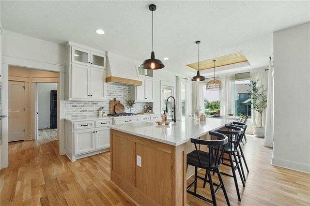 16555 S Lichtenauer Dr, Olathe, KS 66062 - kitchen featuring custom exhaust hood, light wood finished floors, a breakfast bar area, light countertops, and recessed lighting