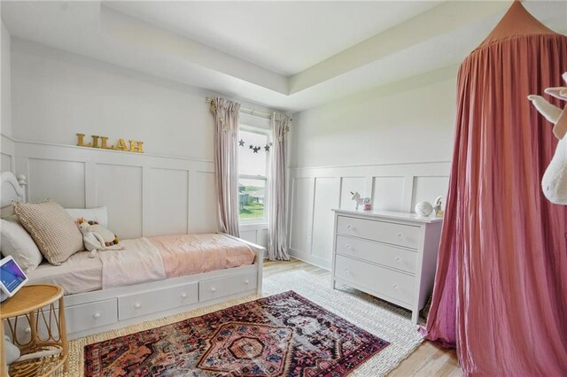16555 S Lichtenauer Dr, Olathe, KS 66062 - bedroom featuring a decorative wall, wainscoting, light wood-style flooring, and a raised ceiling