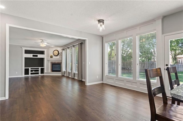 17940 W 158th Ct, Olathe, KS 66062 - unfurnished living room featuring a textured ceiling, a glass covered fireplace, wood finished floors, built in features, and ceiling fan