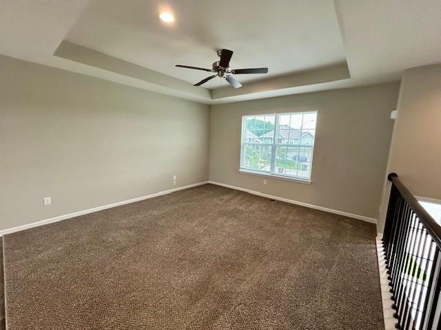 21800 Southcreek Rd, Peculiar, MO 64078 - spare room featuring a raised ceiling, a ceiling fan, and dark carpet