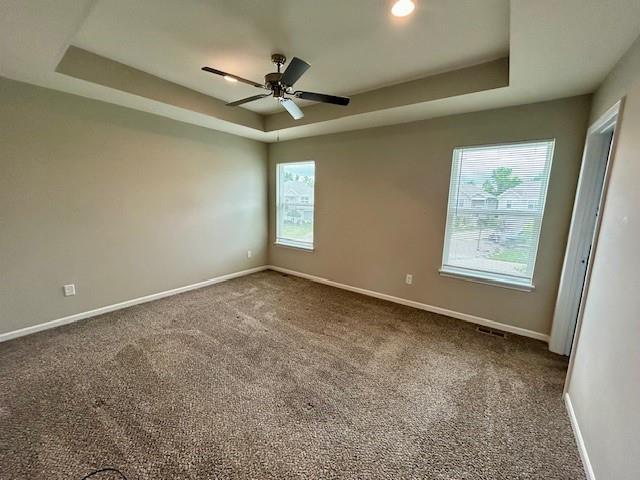 21800 Southcreek Rd, Peculiar, MO 64078 - empty room featuring a tray ceiling, carpet flooring, and a ceiling fan