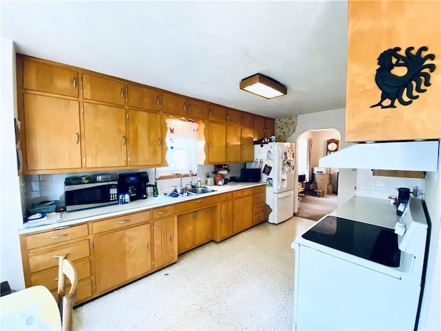 311 SW 12th Ter, Concordia, MO 64020 - kitchen with a sink, white appliances, under cabinet range hood, arched walkways, and decorative backsplash