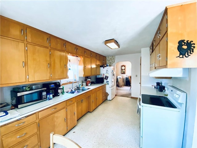 311 SW 12th Ter, Concordia, MO 64020 - kitchen featuring white appliances, a sink, under cabinet range hood, arched walkways, and light countertops