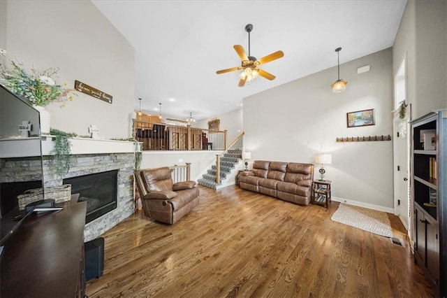 14115 NW 68th St, Parkville, MO 64152 - living room featuring a stone fireplace, ceiling fan, stairway, and wood finished floors