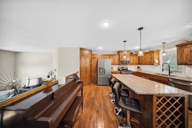 14115 NW 68th St, Parkville, MO 64152 - kitchen featuring stainless steel appliances, light wood finished floors, a center island, decorative backsplash, and decorative light fixtures