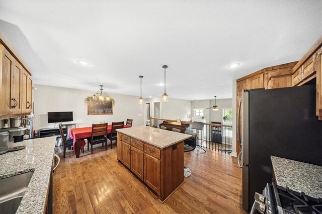 14115 NW 68th St, Parkville, MO 64152 - kitchen featuring brown cabinets, wood finished floors, a kitchen island, freestanding refrigerator, and recessed lighting