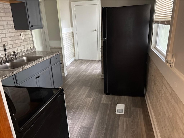 3307 Askew Ave, Kansas City, MO 64128 - kitchen featuring black appliances, dark wood-type flooring, gray cabinets, backsplash, and light countertops
