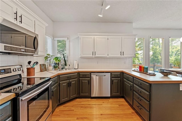 9000 W 127th Ter, Overland Park, KS 66213 - kitchen with stainless steel appliances, a peninsula, white cabinets, light wood-style flooring, and a textured ceiling