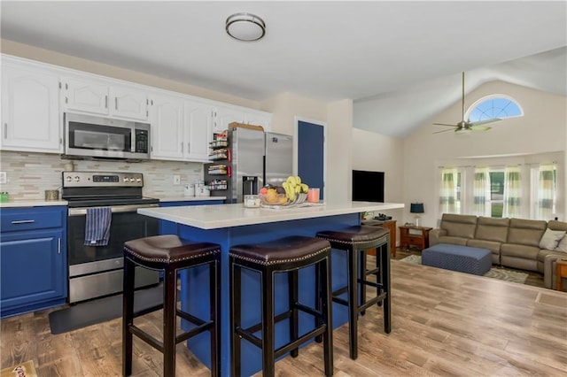 15375 Roger Rd, Leavenworth, KS 66048 - kitchen with appliances with stainless steel finishes, blue cabinetry, a kitchen breakfast bar, lofted ceiling, and light countertops