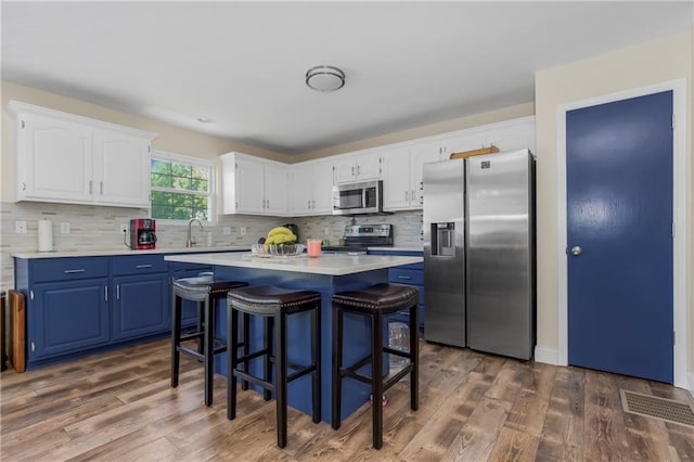15375 Roger Rd, Leavenworth, KS 66048 - kitchen featuring stainless steel appliances, blue cabinetry, light countertops, white cabinets, and a center island