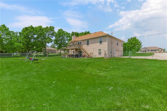 15375 Roger Rd, Leavenworth, KS 66048 - back of house with stairs, an attached garage, a deck, stucco siding, and a playground