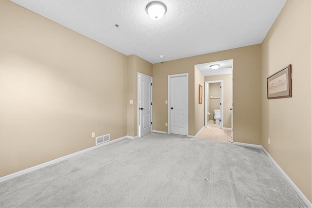 15723 W 61st Ter, Shawnee, KS 66217 - unfurnished bedroom featuring a textured ceiling, light colored carpet, and ensuite bath