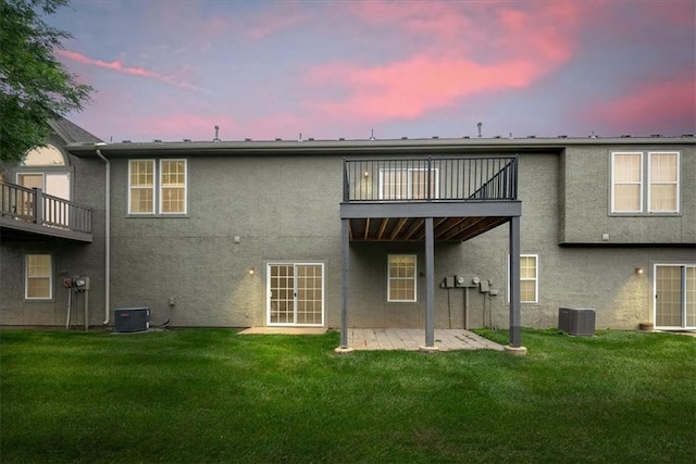 15723 W 61st Ter, Shawnee, KS 66217 - back of house at dusk featuring stucco siding, a patio, a balcony, a yard, and french doors
