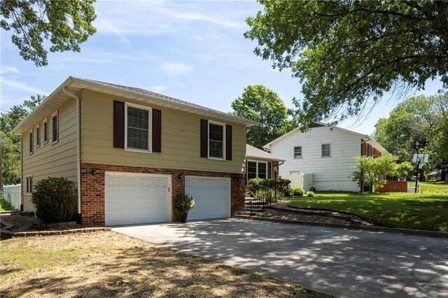 315 Goodrich Dr, Warrensburg, MO 64093 - view of front facade featuring brick siding, an attached garage, driveway, and a front lawn